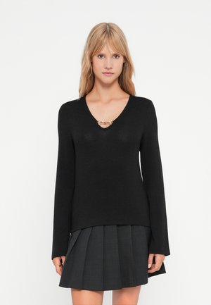 Pull noir à manches longues avec un col en V et un accent décoratif doré au niveau de l'encolure. Texture douce et design ajusté.