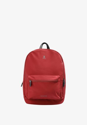Mochila de nailon roja con un gran compartimento principal, bolsillo frontal con cremallera y detalles en cuero negro. Presenta un logo de calavera en la parte superior.