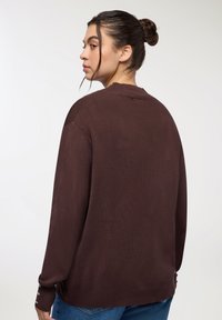 Maglione marrone, dalla vestibilità ampia, con texture a coste e dettagli con bottoni sulle maniche. Vista posteriore, caratterizzato da un colletto rotondo e design informale.