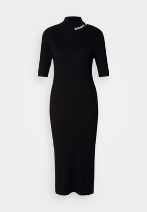 Melnas ribotu adījumu kleitas ar īsām piedurknēm, augsto kaklu un DKNY logotipu ap kakla izgriezumu. Kaķkājas piegriezums, vidēja garuma siluets.