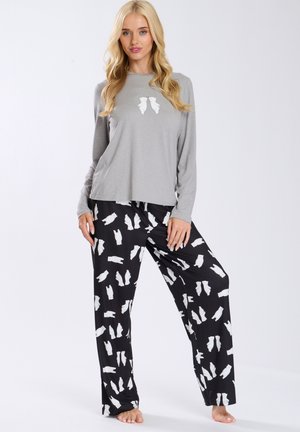 Maglietta grigia a maniche lunghe con un design grafico giocoso, abbinata a pantaloni neri con motivo orso bianco. Vestibilità morbida e rilassata.