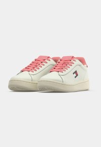 Λευκά δερμάτινα αθλητικά παπούτσια με ροζ κορδόνια  και λεπτομέρειες στη φτέρνα. Διαθέτουν λογότυπο σε κόκκινο και μπλε. Λαστιχένια σόλα με ανάγλυφο σχέδιο για καλύτερο κράτημα.