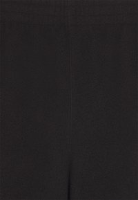 Svarta stretchbyxor i tyg med en slät yta, featuring ett brett elastiskt midjeband och minimal detallering.