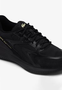 Czarne sportowe buty wykonane z siateczki i zamszu, z teksturowanymi detalami, płaskimi sznurowadłami oraz małym złotym logo akcentującym przy kołnierzu.