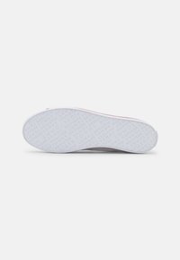 Sole di scarpa bianca con superficie testurizzata che presenta il logo del marchio ripetuto in grigio chiaro. Bordo esterno liscio con un sottile accento rosa attorno al bordo.