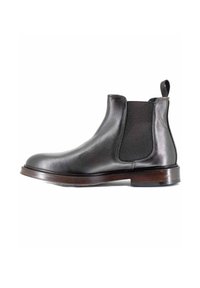 Stivale Chelsea in pelle nera con pannelli laterali elasticizzati, punta arrotondata, tacco impilato e linguetta. Finitura liscia con una silhouette elegante.