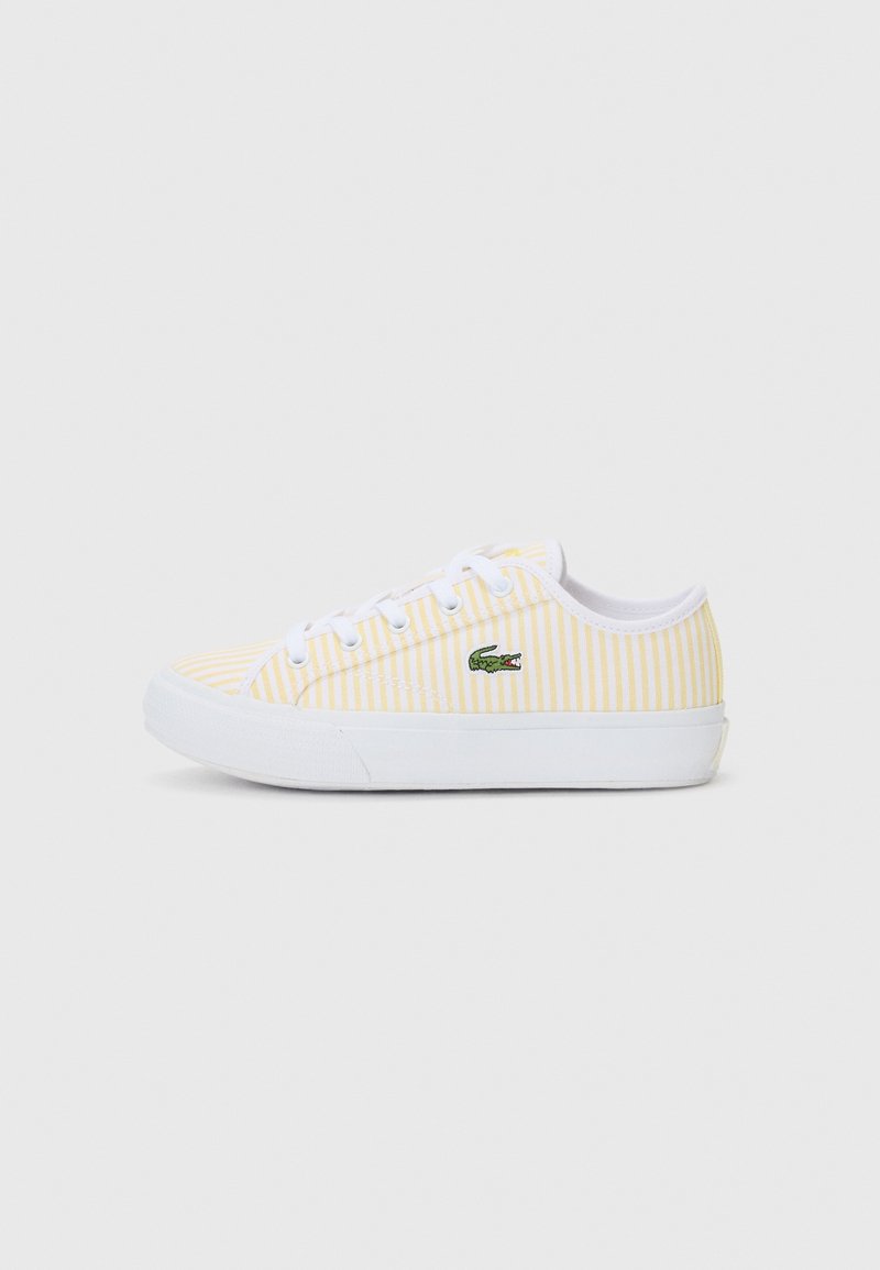 Baskets basses avec semelle et lacets blancs, rayures verticales jaunes et blanches, et un logo crocodile vert sur le côté.