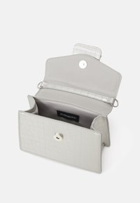 Mały portfel ze srebrnej sztucznej skóry o fakturze krokodyla. Wyposażony w zatrzask oraz przegródkę na karty. Wnętrze wyściełane miękkim materiałem.