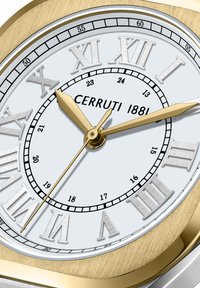 Reloj en tono dorado con una esfera blanca redonda, números romanos, marcadores de minutos en negro, agujas doradas y una caja metálica con un acabado cepillado.