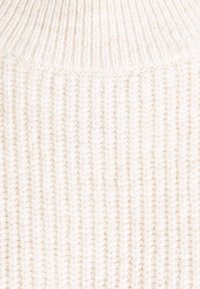 Sweter dziergany z wysokim ściągaczem, wykonany z miękkiej, kremowej włóczki, z pionowym wzorem ściągacza na całej powierzchni.