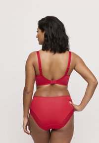 Conjunto de lencería roja que incluye un sujetador liso con tirantes ajustables y una braguita de talle alto a juego, ambos con detalles de encaje.