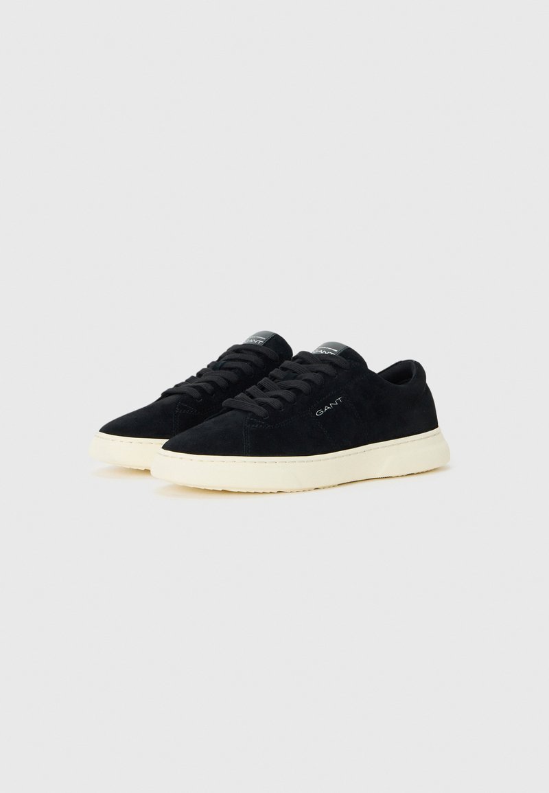 Par svart mocka låga sneakers med svarta snören och avvikande vita gummisålar, märkt med "GANT" på sidan och tungan.