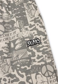 Grijs camouflagepatroon stof met verschillende graphics, waaronder tekst en afbeeldingen, en een zwart 'Grimy' logo patch.