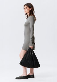 Rochie gri cu mânecă lungă, cu un corp ajustat și o siluetă lejeră, asortată cu o geantă mare din suede negru, cu studuri argintii.