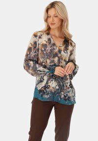 Bluzka z długim rękawem i dekoltem w kształcie litery V w kwiatowy wzór w odcieniach ziemi i akcentach w odcieniach teal; wykonana z miękkiego, zwiewnego materiału, z falbaniastymi mankietami i dołem.