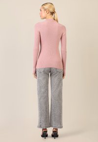 Fitted, geripptes, rosa Langarmoberteil kombiniert mit grauen, weit geschnittenen Jeans, die verstreute hellblaue Verzierungen aufweisen. Glatte Textur; minimalistisches Design.