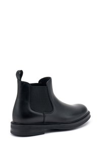 Stivale Chelsea in pelle nera con pannelli elasticizzati ai lati, una linguetta sul retro e una tomaia liscia con punta rotonda e suola piatta in gomma.