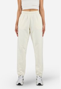 Crèmekleurige sweatpants met een elastische tailleband en zijzakken, voorzien van een zachte textuur en subtiele logo-detail op de dij.