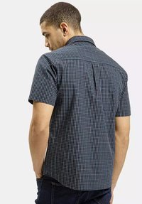 Koszula w kratę w kolorze granatowym z krótkim rękawem, wykonana z lekkiego materiału, z kołnierzykiem, karczkiem z tyłu i prostym dołem.