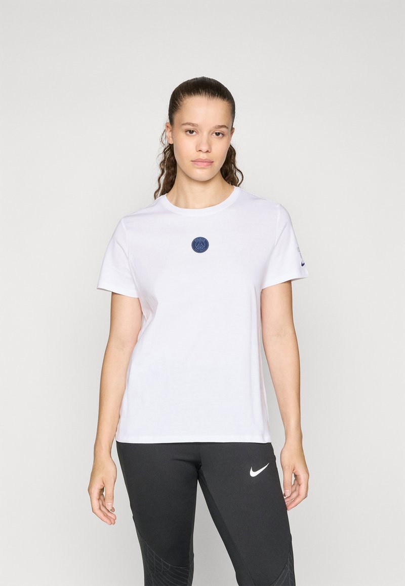 White cotton t-shirt with a round neckline and a navy logo patch at the center. Paired with black leggings featuring a Nike logo.