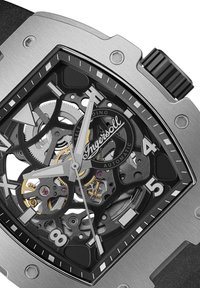Zwart skeleton wijzerplaat horloge met zilveren accenten, metalen kast en een gestructureerde rubberen band. Bevat zichtbare tandwielen en een automatisch opwindmechanisme.