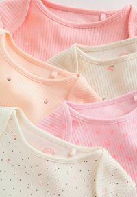 Penki kūdikių smėlinukai iš gofruoto audinio, švelnių pastelinių spalvų: rožiniai, persikiniai ir kreminiai, su mažais raštais, tokiais kaip širdelės ir vyšnios.