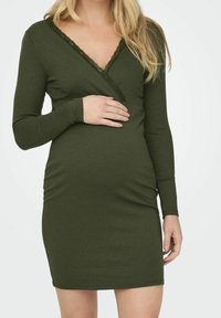 Mörkgrön ribbad klänning med långa ärmar, djup V-ringning och spetsdetaljer. Designad för komfort med en figurnära passform för en snygg look.