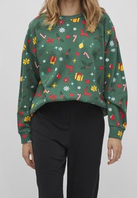 Grön sweatshirt i mjukt tyg, med ett festligt mönster av röda renar, färgglada julklappar och snöflingor. Lös, kort design.