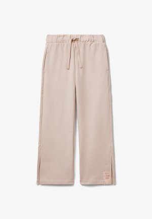Pantaloni tuta larghi color rosa chiaro con elastico in vita, coulisse, tasche laterali, piccoli spacco laterale e una toppa con la scritta "DIVERTITI RAGAZZA" vicino all'orlo.