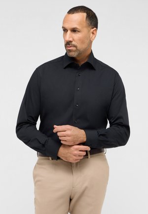 Schwarzes Langarmshirt mit klassischem Kragen, knopfbarem Vorderteil und tailliertem Schnitt. Mit maßgeschneiderten Manschetten und glatter Stofftextur.