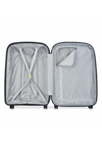 Valise rigide noire ouverte, présentant un intérieur gris avec des sangles élastiques diagonales, une poche en maille zippée et un revêtement texturé.