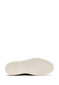White rubber outsole with textured grip pattern, rounded shape, and minimal branding near the heel. Back edge features a slight arch.