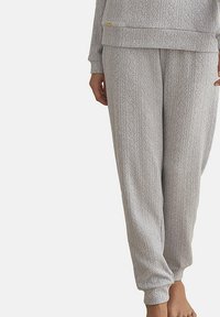 Lichtgrijze pyjamabroek met een gestructureerd patroon, voorzien van verticale strepen en ruitenmotieven. De boorden zijn elastisch voor een goede pasvorm.