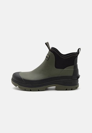 Grüne Gummistiefel bis zum Knöchel mit schwarzem Obermaterial, strukturiertem Rand und einer stabilen, schwarzen Sohle mit tiefen Profilen für Grip. Barbour-Logo an der Seite.