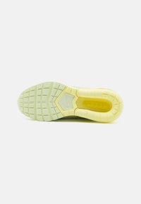 Semelle de sneaker en vert clair et jaune. Caoutchouc texturé avec un motif hexagonal et une unité de coussin d'air visible. Logo Nike présent.