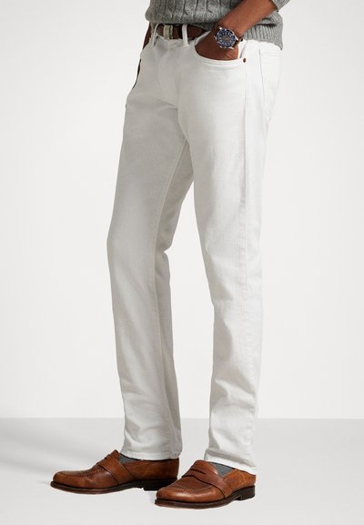 Pantalones de algodón blancos con diseño de pierna recta, que cuentan con bolsillos frontales y un ajuste casual, combinados con mocasines de cuero marrón.