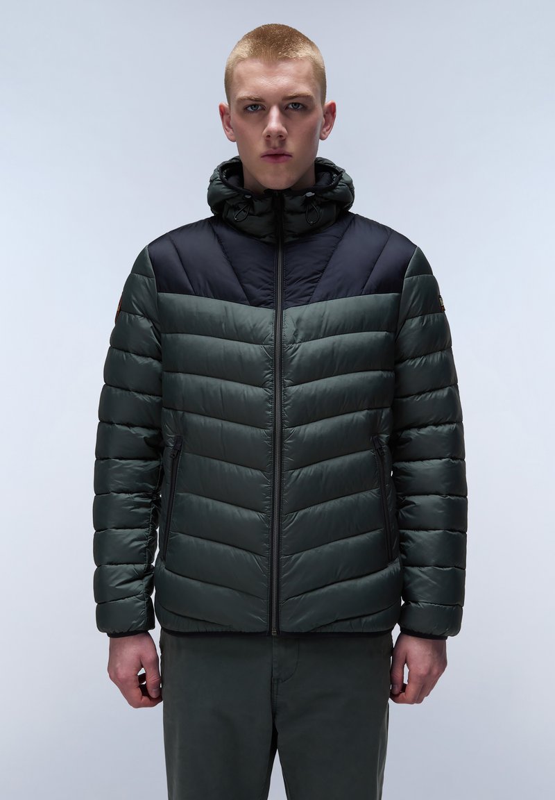 Giacca imbottita di colore verde scuro, con cappuccio nero e accenti sulle spalle, chiusura con zip e motivo a zig-zag. Texture morbida e lucida.