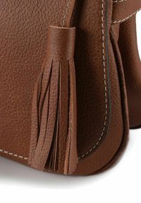 Braune Ledertasche mit strukturierter Oberfläche, einem Quastenanhänger mit Fransen und kontrastierenden Nähten entlang der Kanten.