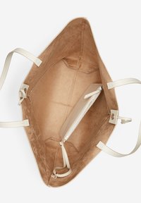 Intérieur d'un sac fourre-tout en daim beige avec des sangles lisses et claires. Comprend une poche zippée et une forme structurée avec un compartiment spacieux.