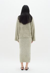 Ljusgrön stickad set bestående av en kortärmad tröja och en knälång kjol med en fluffig textur. Svarta remsandaler.
