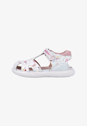 Sandalias blancas para niños con recortes, patrones de flores y mariposas, correa de velcro, interior acolchado en rosa y suela de goma blanca.