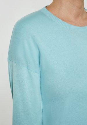 Jasnoniebieski sweter z okrągłym dekoltem i długimi rękawami. Materiał wydaje się miękki o gładkiej fakturze oraz subtelnych prążkowanych detalach na dolnym brzegu.