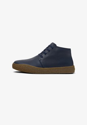 Botines de cuero azul marino con punta redondeada, cuatro ojales para cordones y suela de goma texturizada natural.