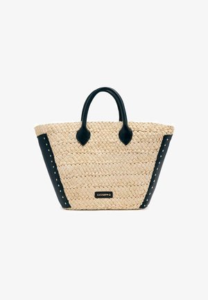 Bolsa de paja trenzada con acentos en cuero negro, que cuenta con dos asas superiores y tachuelas decorativas a lo largo de los lados. Logotipo de la marca exhibido.