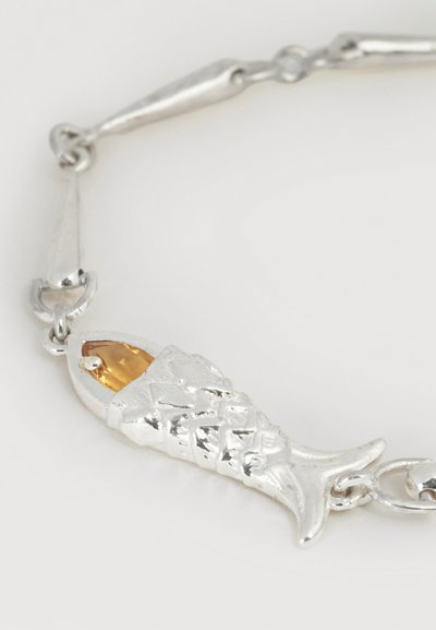 Ασημένιο βραχιόλι με ένα ανάγλυφο γοητευτικό ψάρι που έχει ως μάτι ένα δακρυόμορφο πολύτιμο λίθο κεχριμπαρένιου χρώματος.