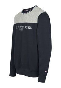 Királykék pulóver szürke vállrésszel, fehér "U.S. POLO ASSN." logóval, kerek nyakkivágással, kontrasztos csíkos részletekkel, bordázott mandzsettákkal.