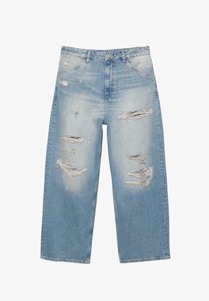 Svetlomodré roztrhané džínsové nohavice s širokými nohavicami, viacerými trhlinami na predných stehnách a vyblednutou rifľovinou.