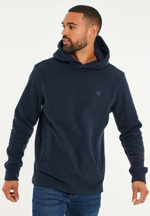 Sudadera con capucha de polar color azul marino, con un bolsillo tipo canguro, puños acanalados y un logo sutil en el pecho. Textura suave y corte relajado.