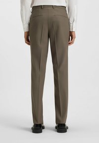Slim-fit, taupe trousers with dual back pockets and creased front. Made of smooth fabric, featuring a belt looped waistband and tailored shaping.