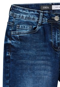 Jean en denim bleu foncé avec une finition délavée, présentant une poche avant, une fermeture par bouton argenté et des détails de couture contrastants.